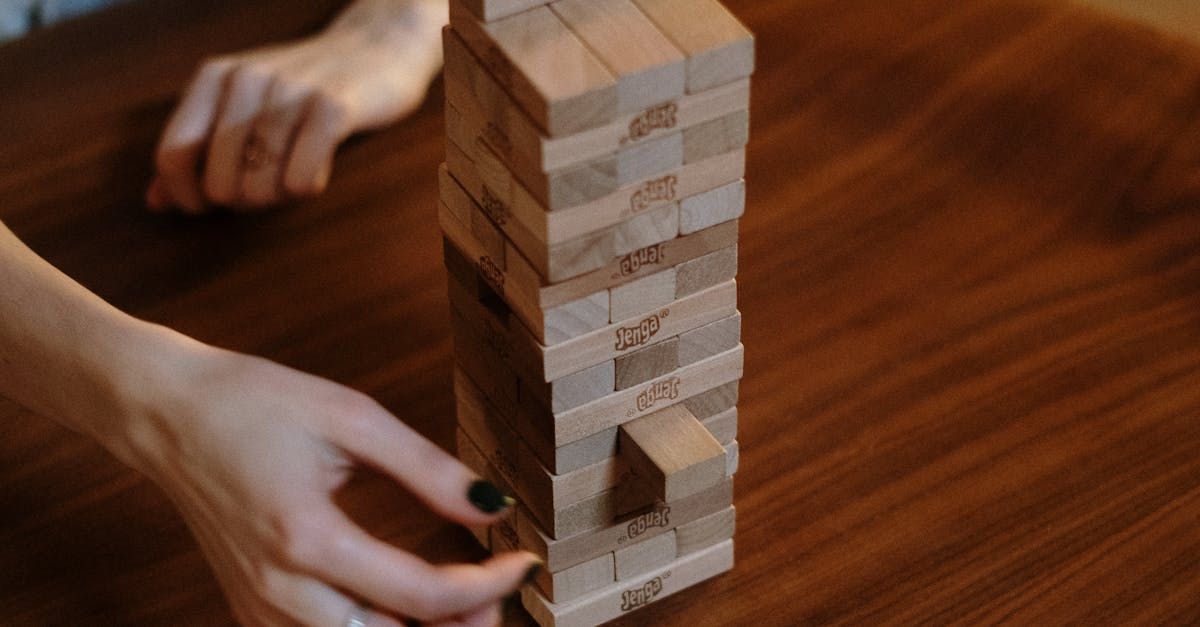 A person is playing jenga on a wooden table.