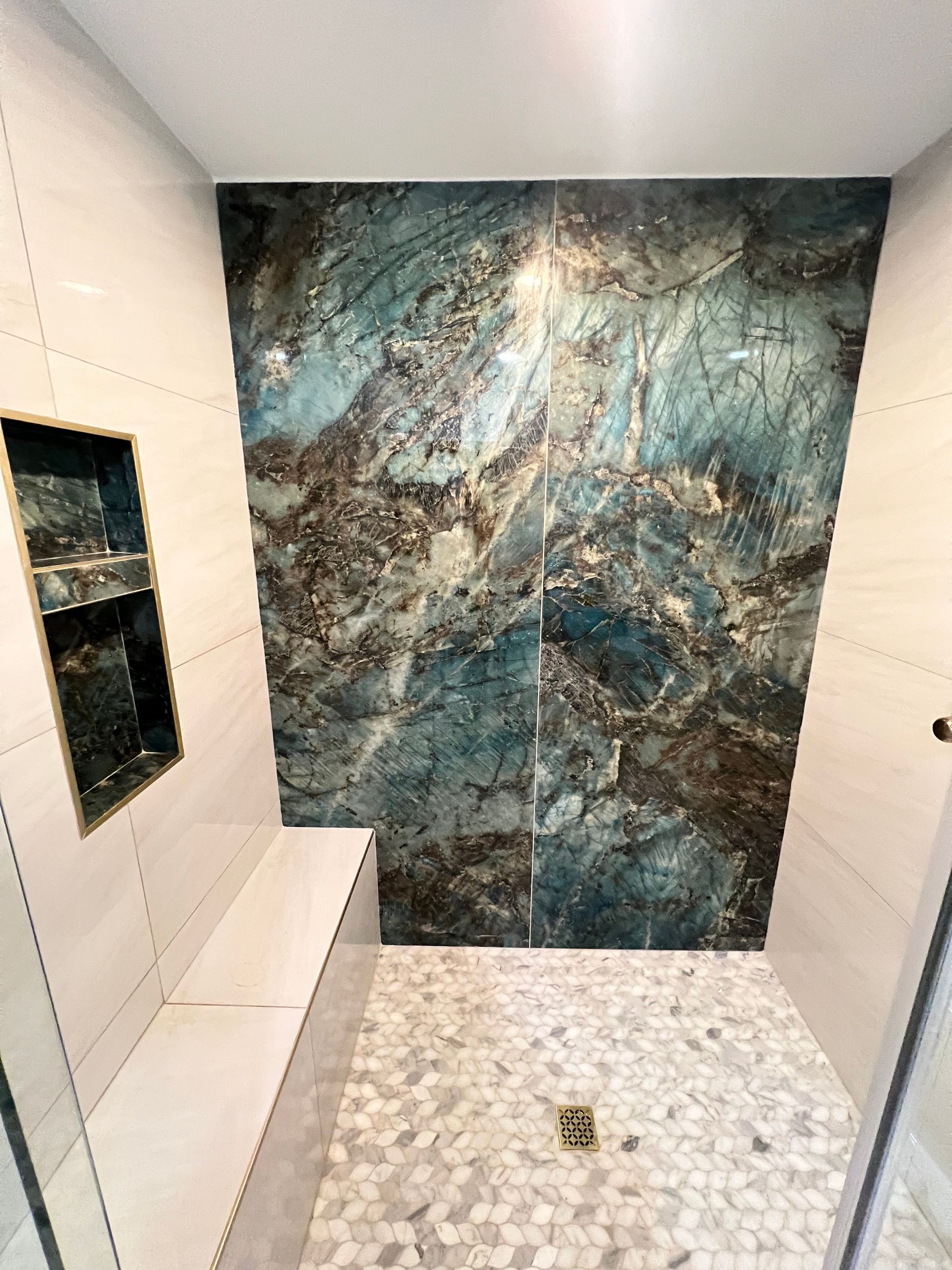A bathroom with white marble tiles and a sink.