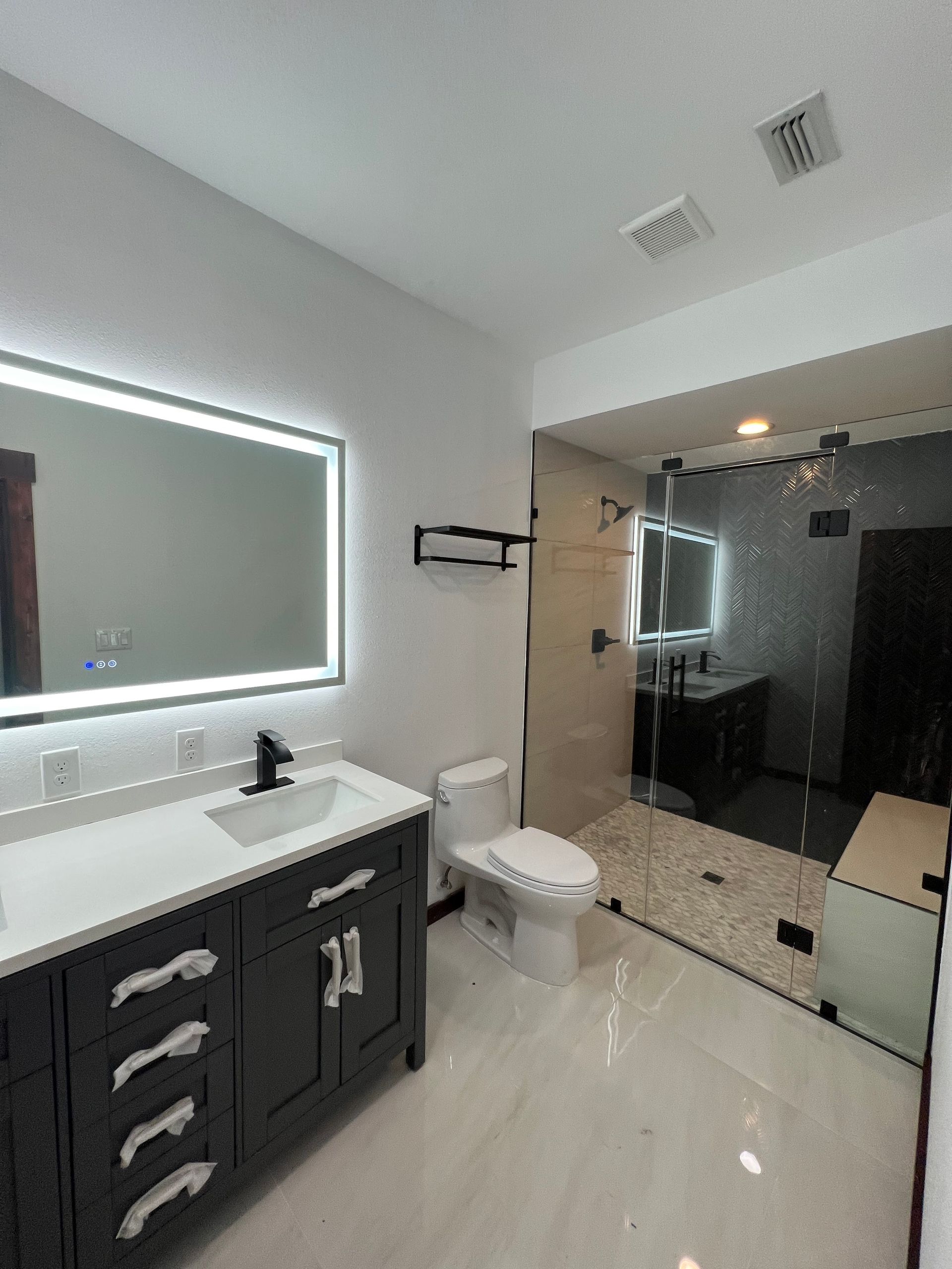 A bathroom with a toilet , sink , mirror and shower.