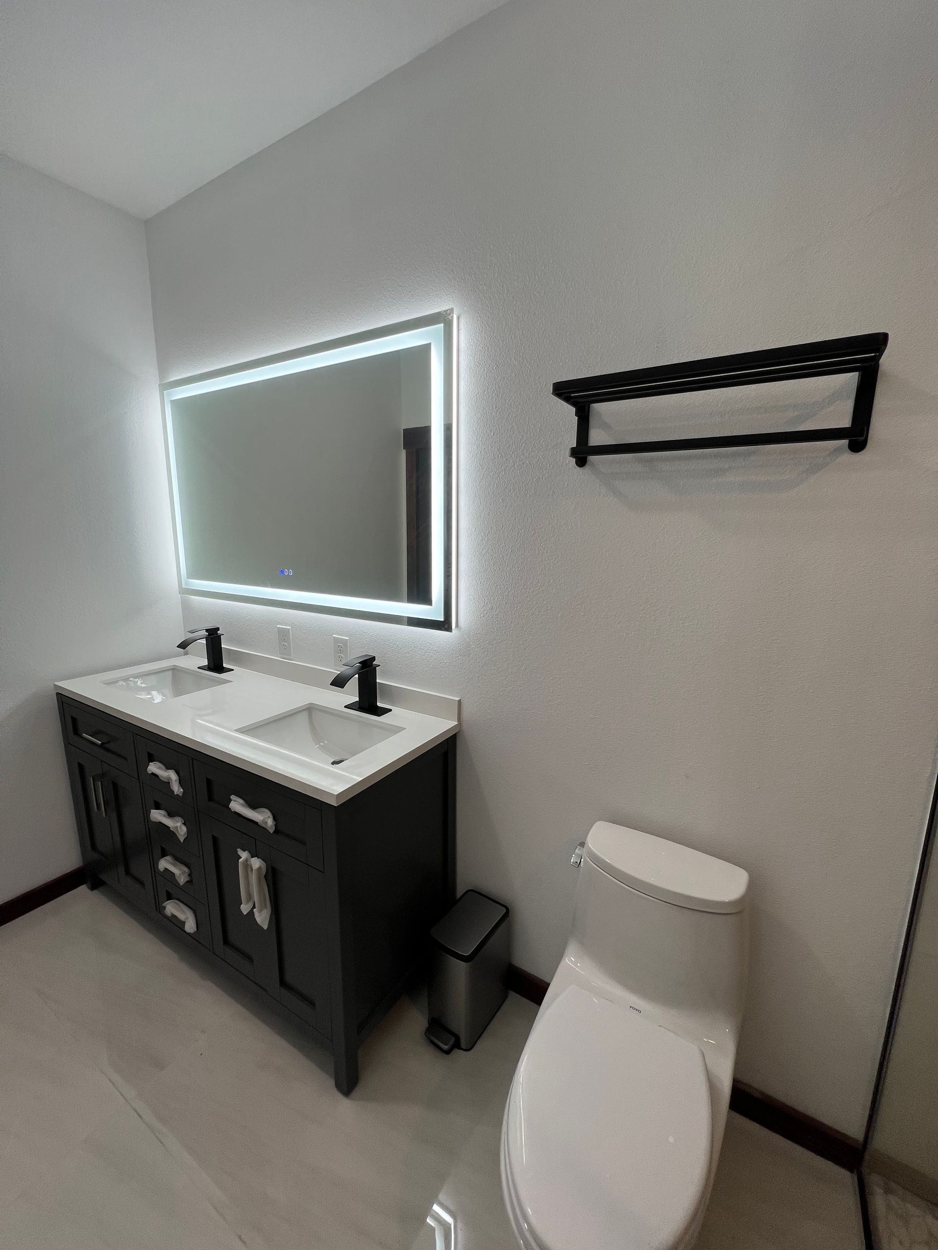A bathroom with a toilet , sink , mirror and towel rack.