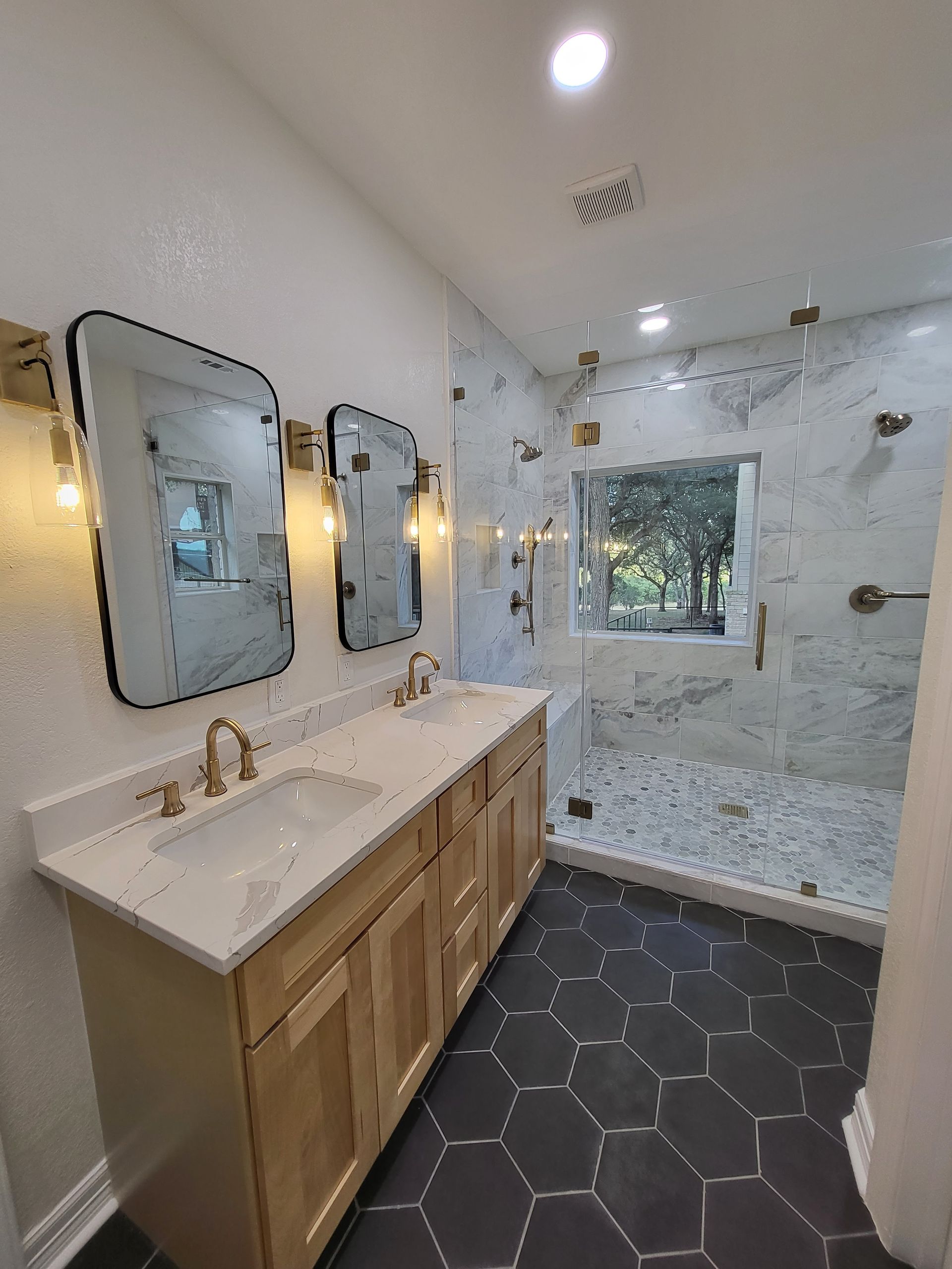 A bathroom with two sinks and a walk in shower.