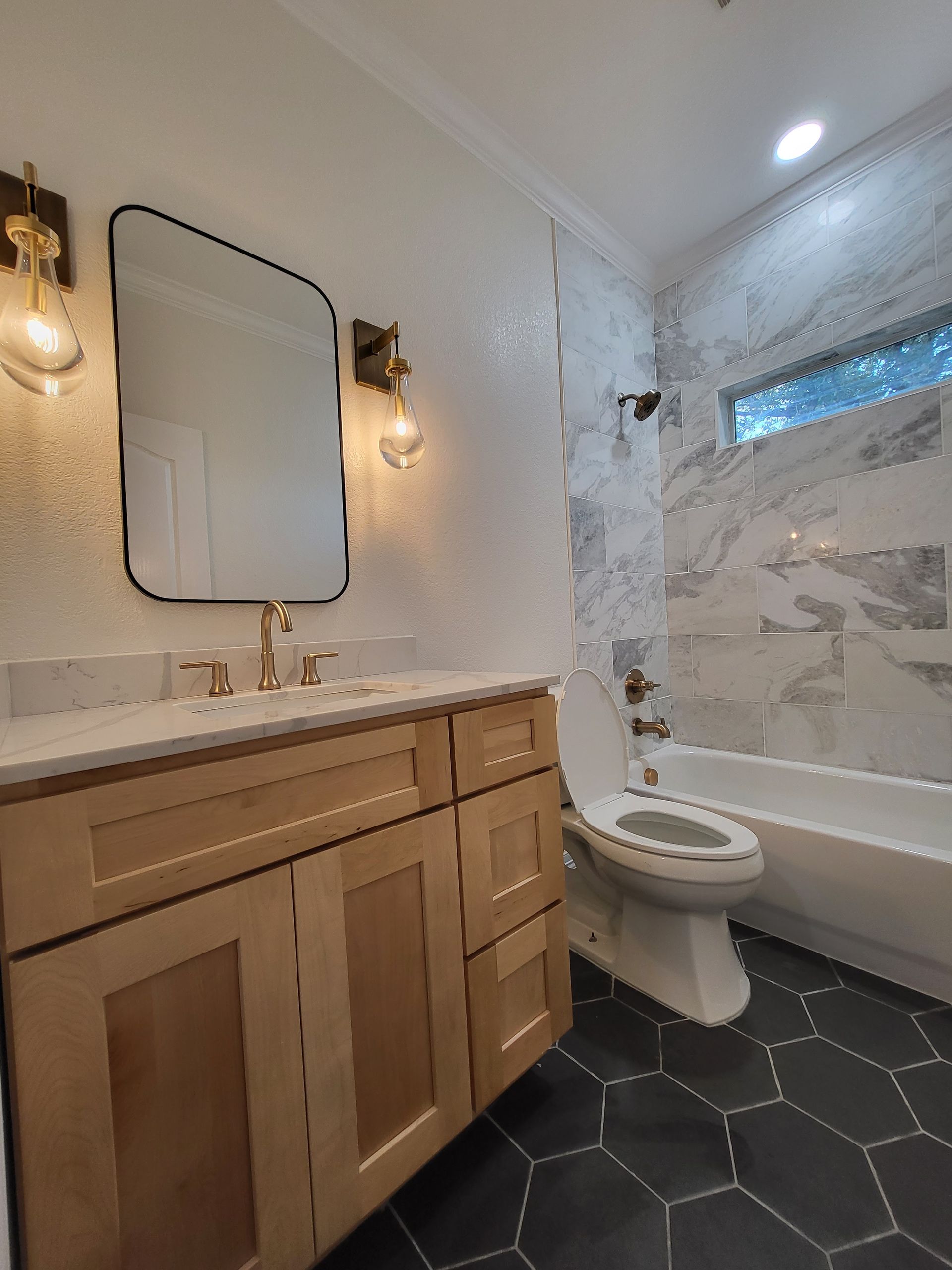 A bathroom with a toilet , sink , mirror and bathtub.