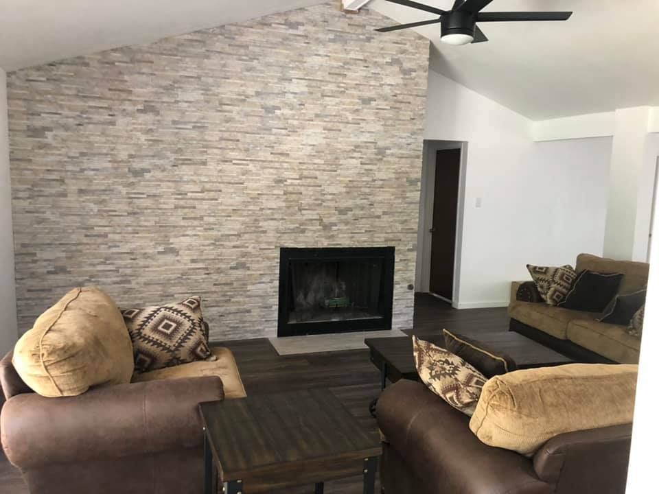 A living room with a fireplace and a ceiling fan