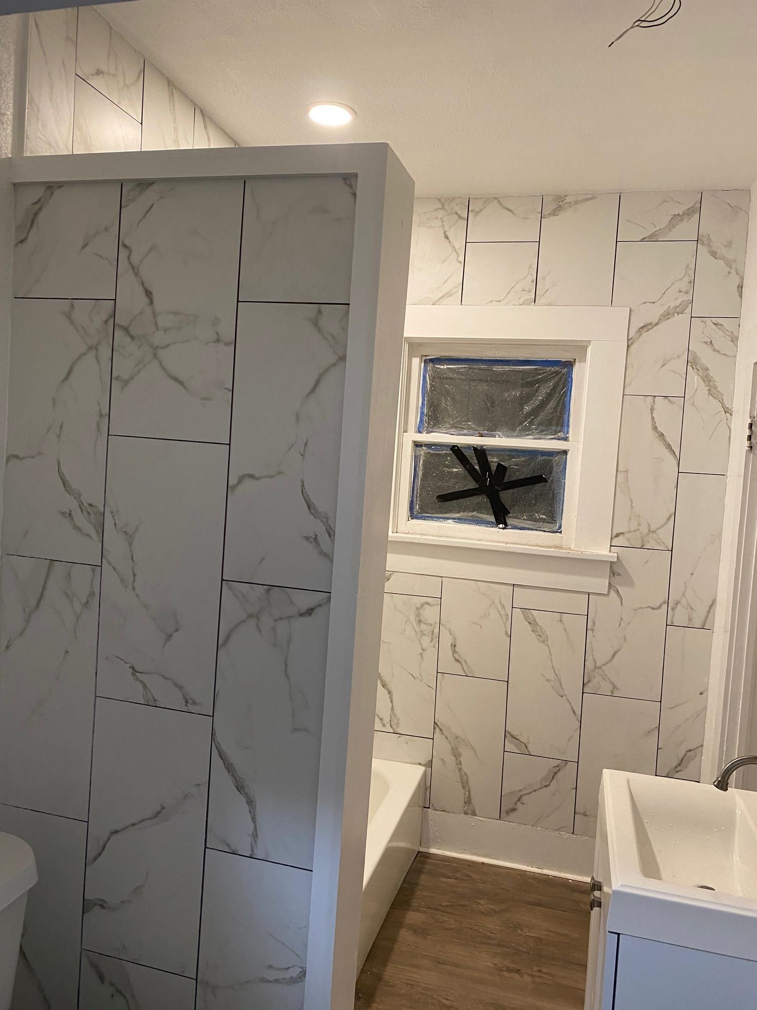 A bathroom with white marble tiles and a sink.