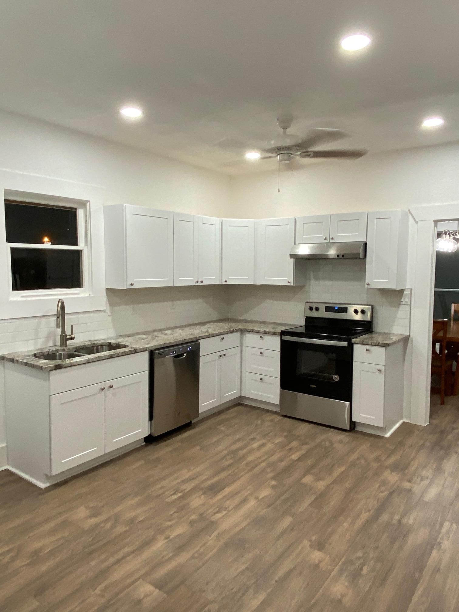 Newly renovated kitchen with white cabinets, stainless steel appliances, and wood-look flooring.