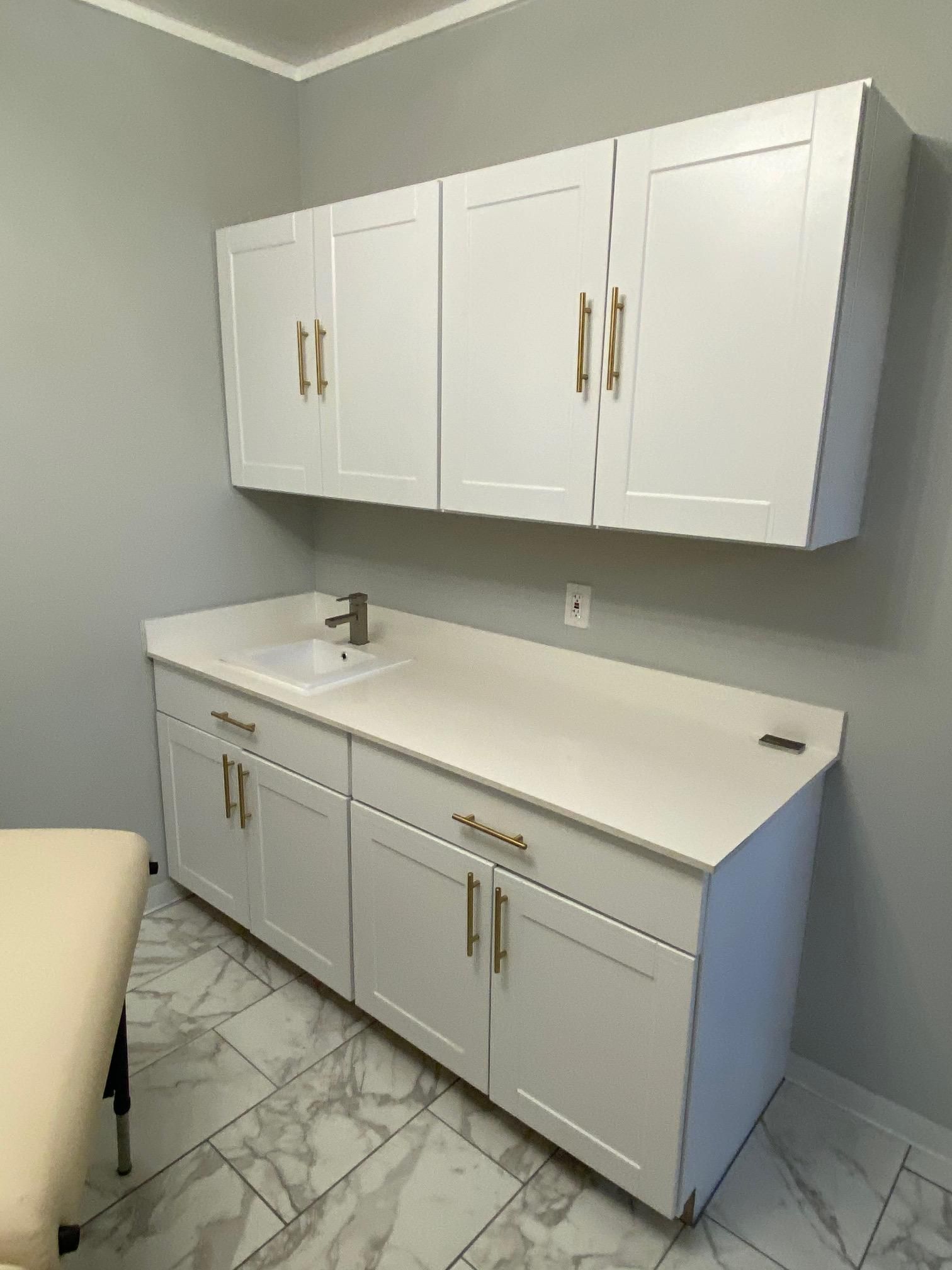 A bathroom with white cabinets and a sink.