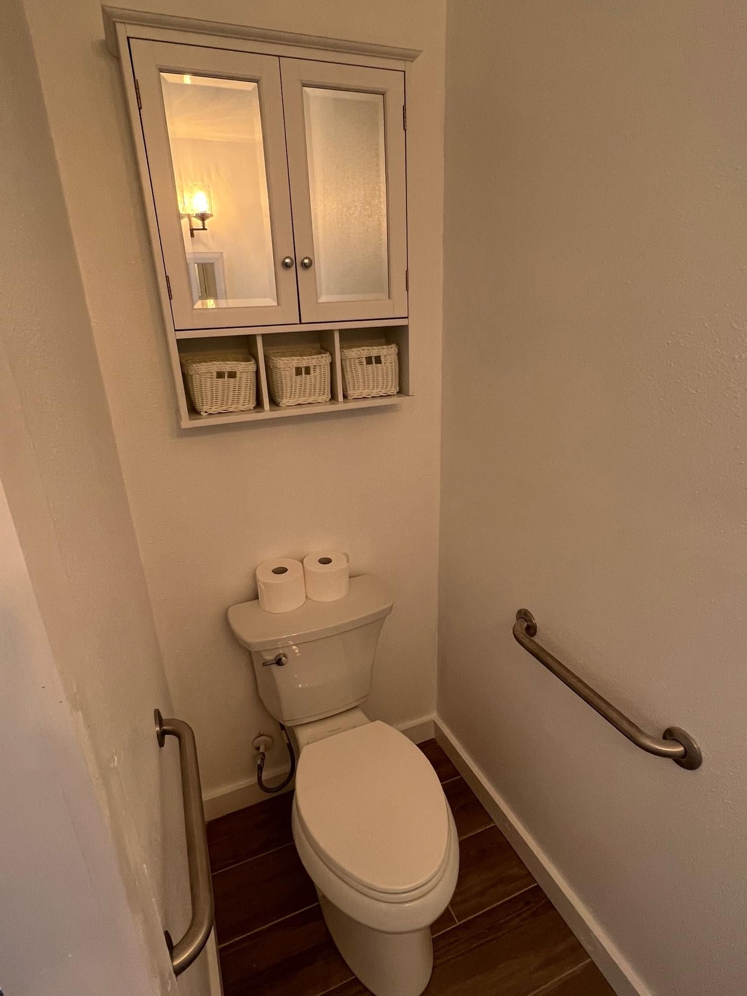 A bathroom with a toilet and a mirror above it.