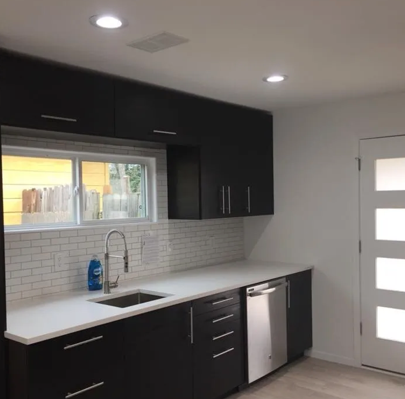 A kitchen with black cabinets and white counter tops