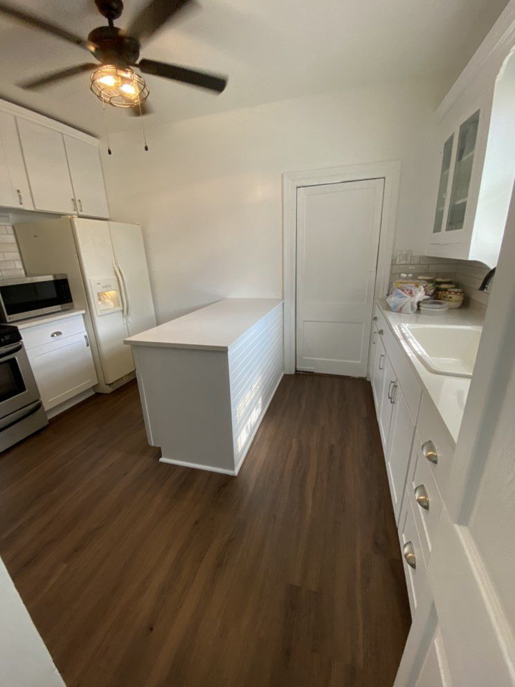 A kitchen with white cabinets and a ceiling fan.