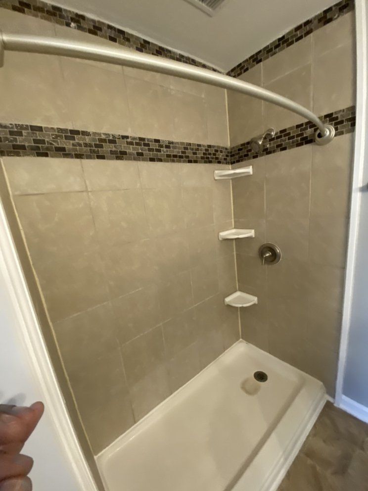 A person is pointing at a shower stall in a bathroom.