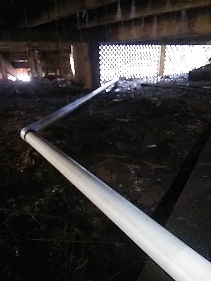 a white pipe is laying on the ground under a home to push water out