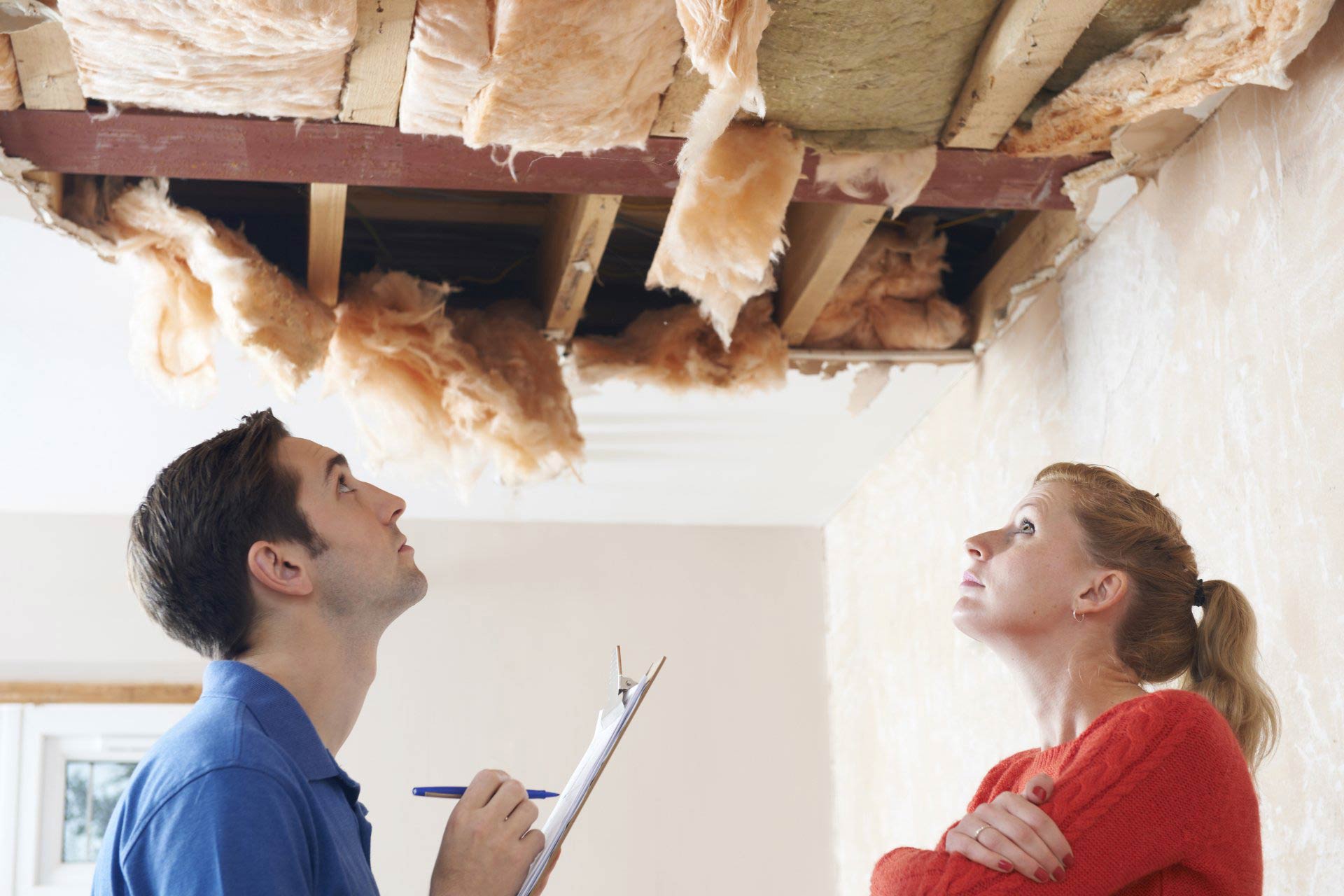 a man and a woman are looking at the ceiling of a house .