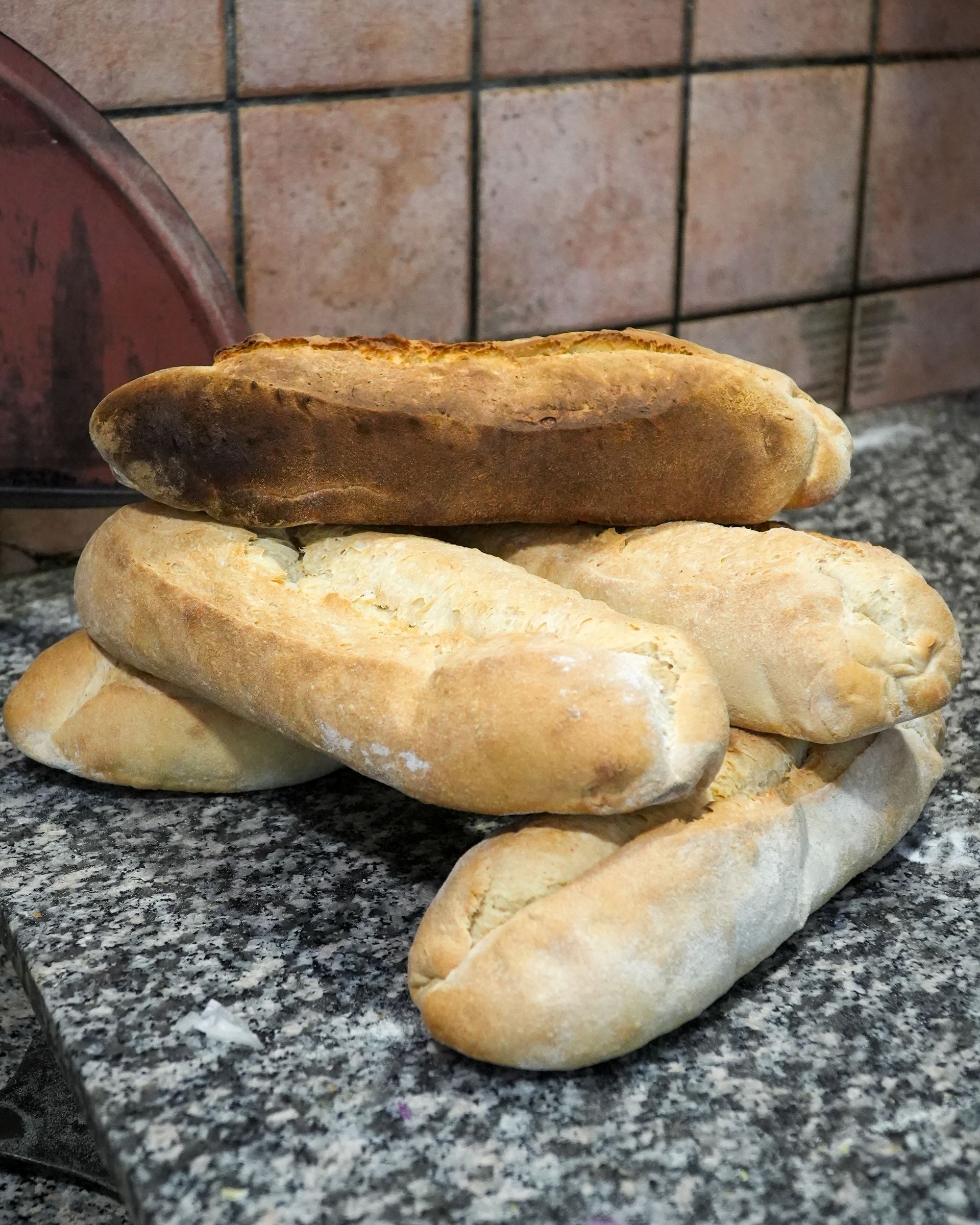 Stack of homemade bread rolls on a kitchen countertop, one roll browned on top.
