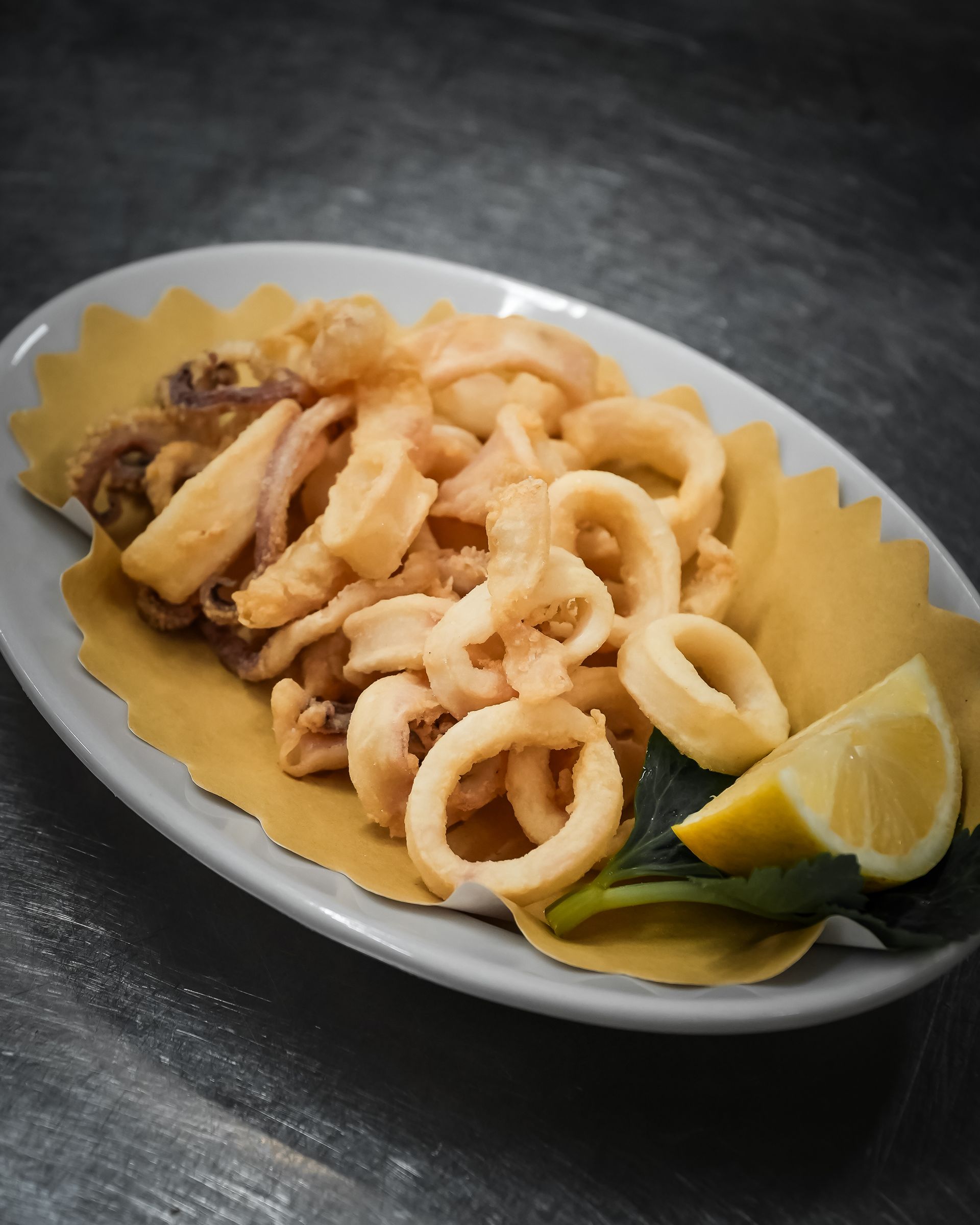 Piatto di calamari fritti con spicchi di limone su un tavolo scuro