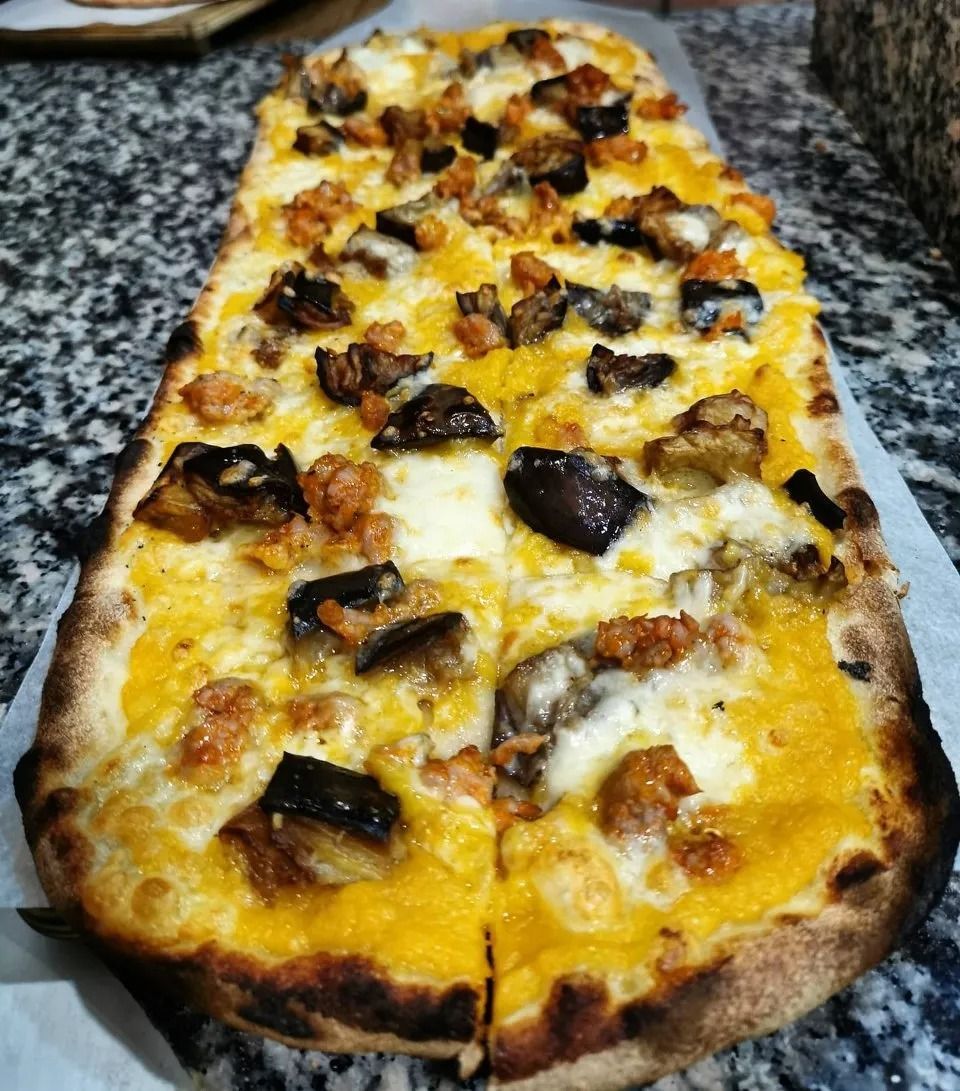 A rectangular cheese and mushroom pizza on parchment paper, with a golden crust and charred spots.