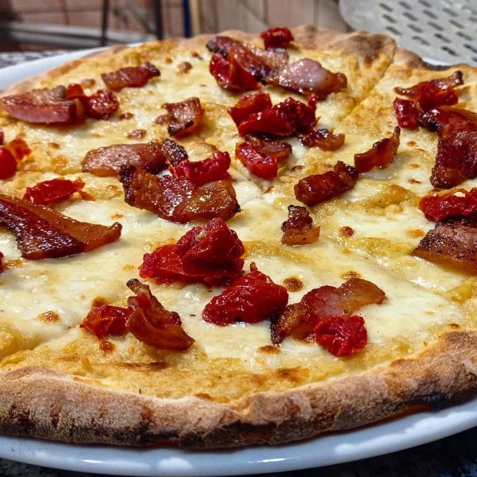 White pizza topped with red sun-dried tomatoes on a plate
