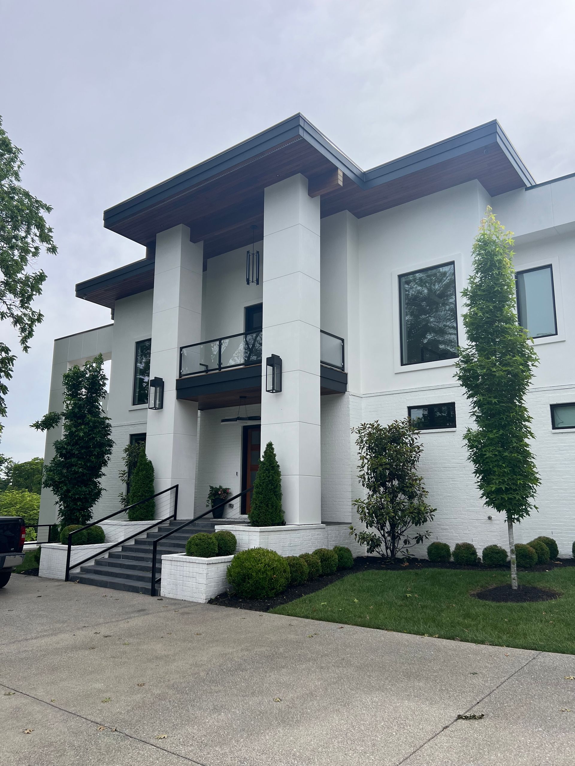 A large white house with a balcony and stairs in front of it.