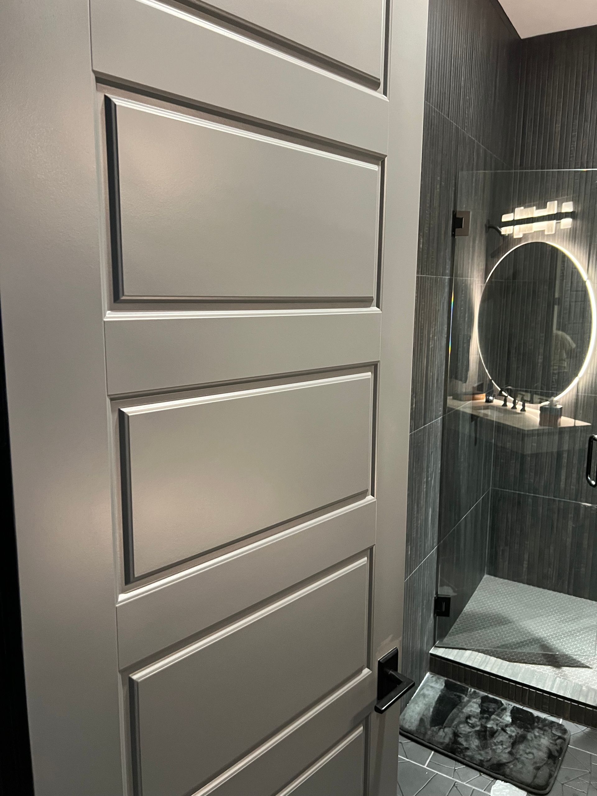 A bathroom with a white door and a mirror.