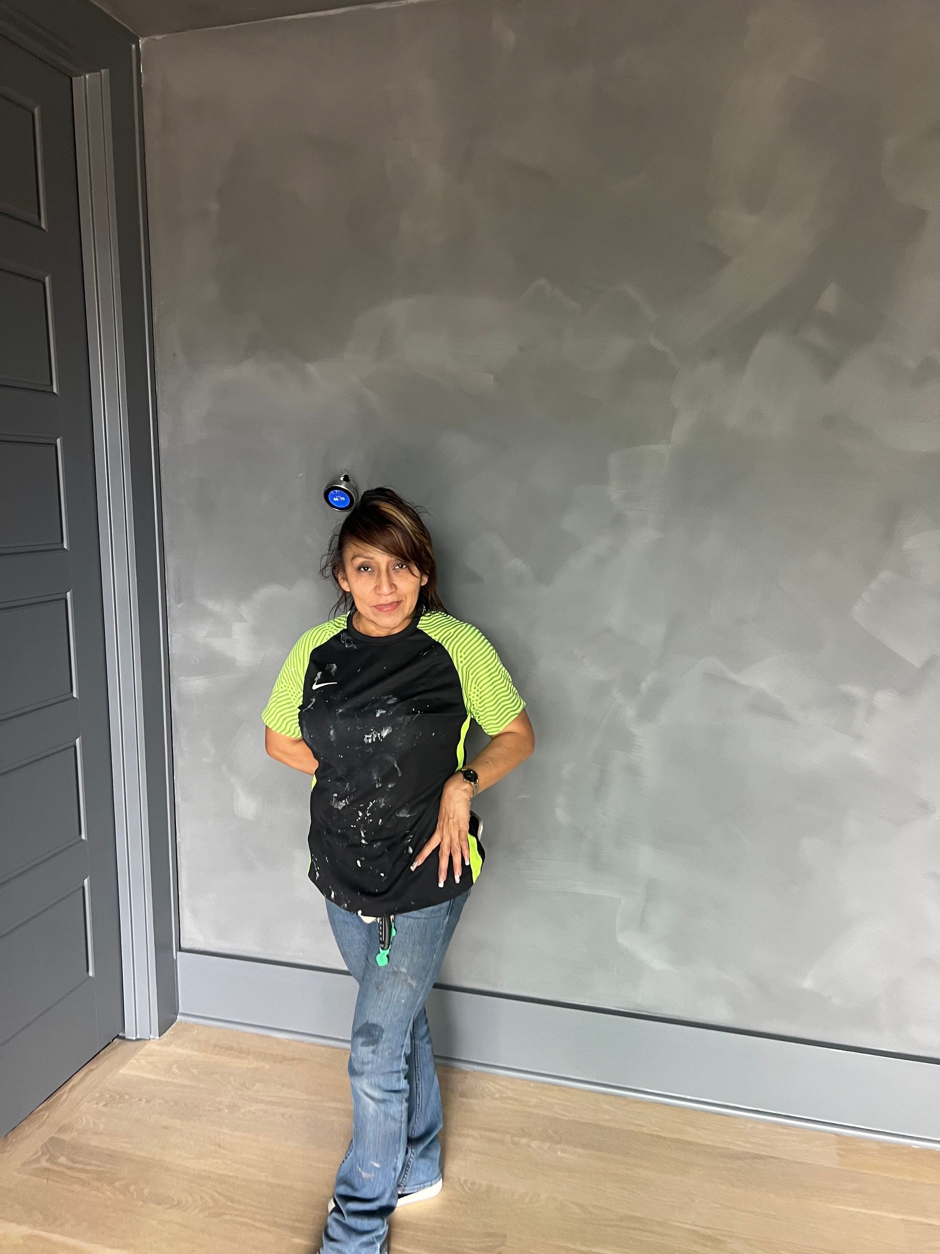 A young girl is standing in a room with a gray wall.