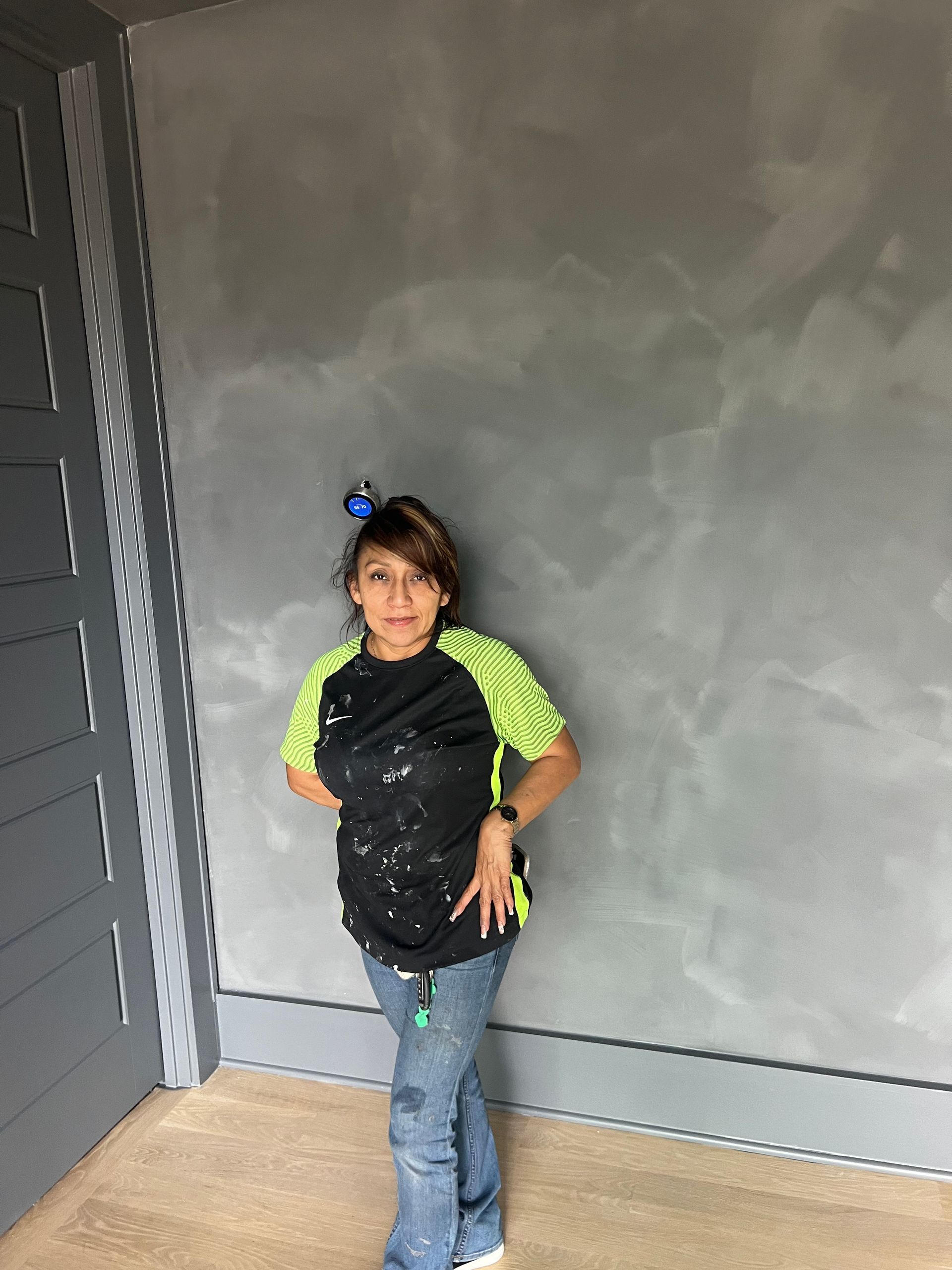 A young girl is standing in a room with a gray wall.