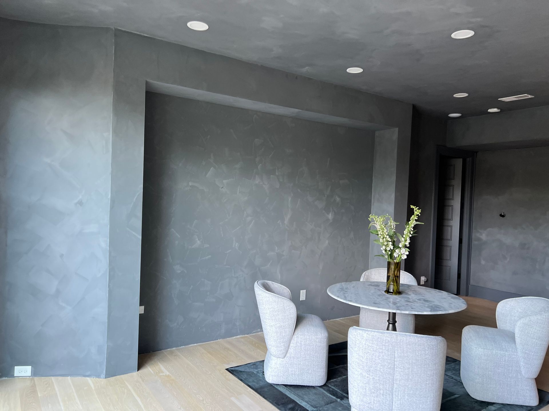 A living room with a table and chairs and a vase of flowers