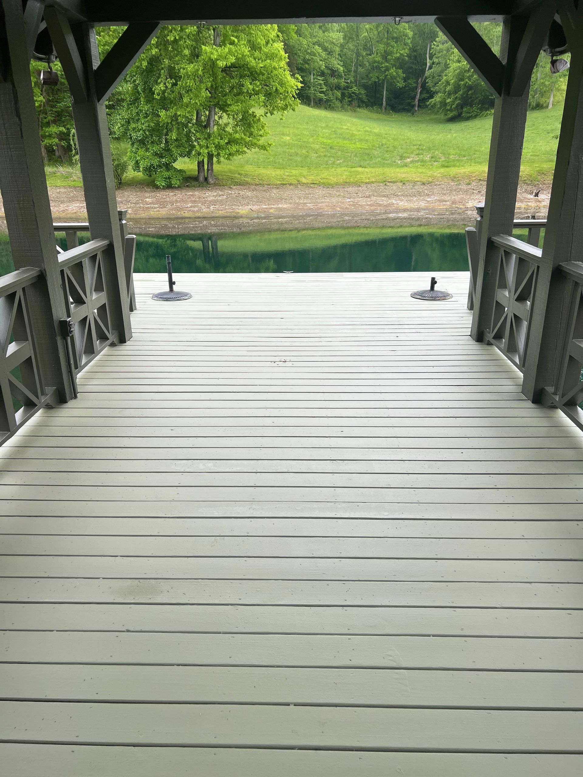 A wooden deck leading to a lake with trees in the background.