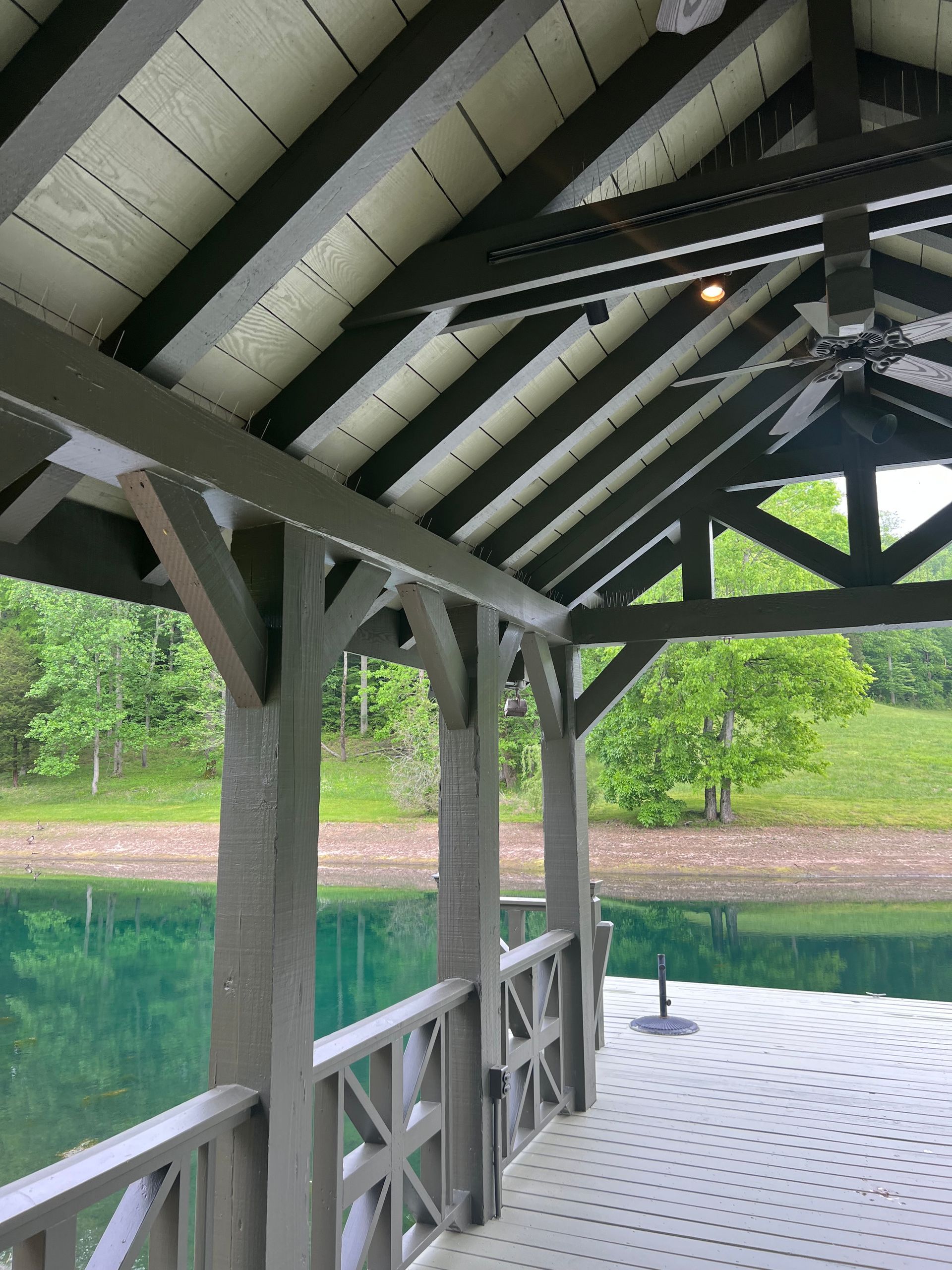 A covered deck overlooking a lake with trees in the background