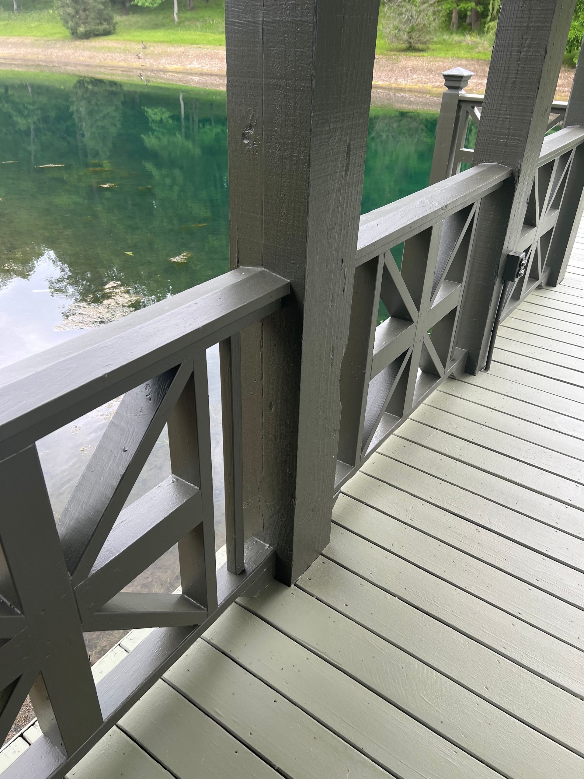 A wooden deck with a railing overlooking a lake.