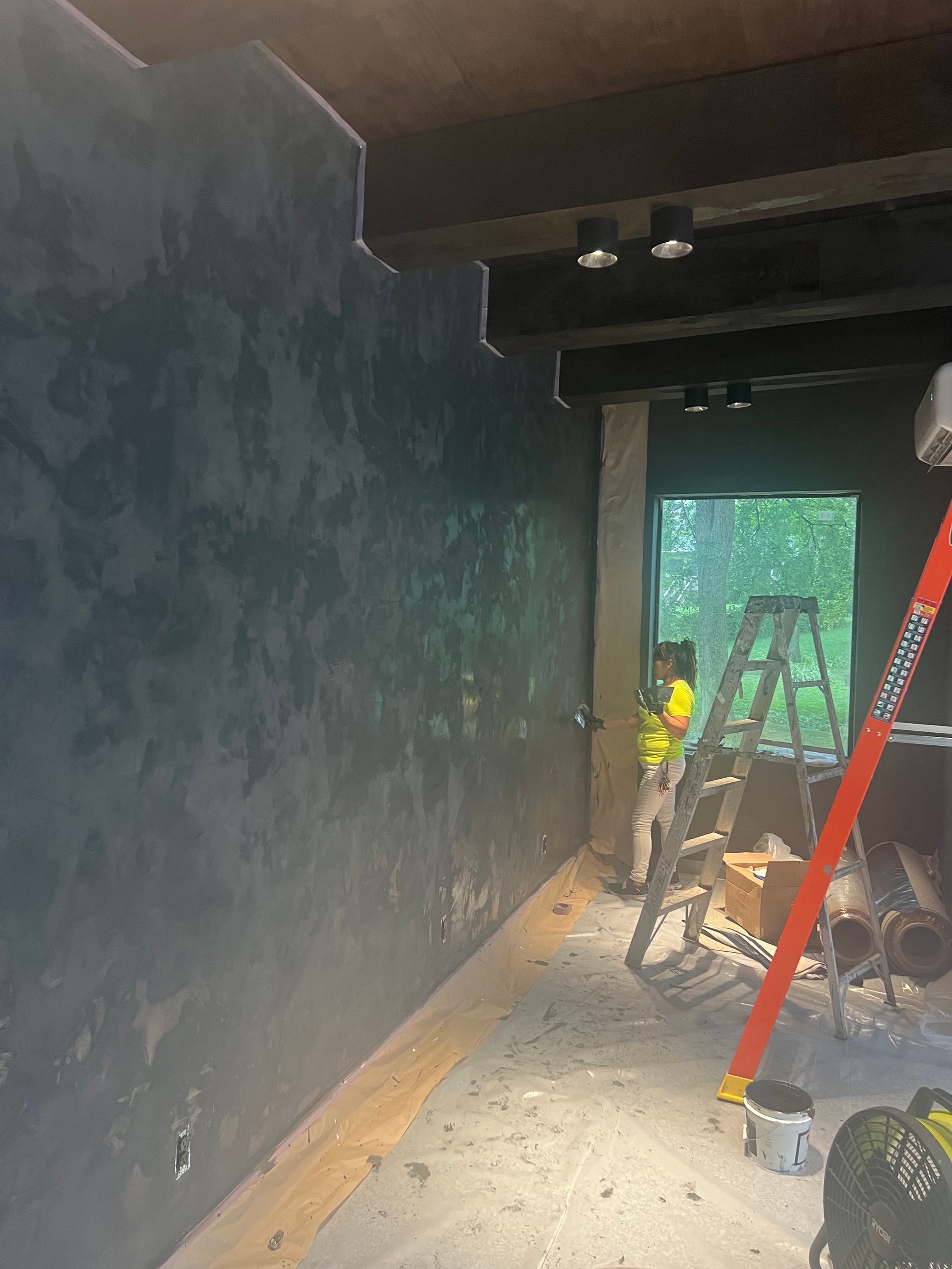 A man is standing next to a ladder in a room.