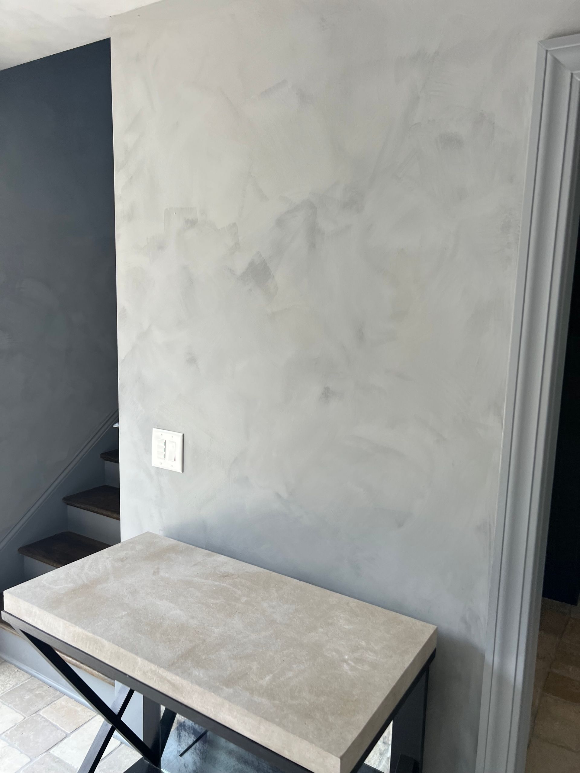 A small table is sitting in front of a gray wall.