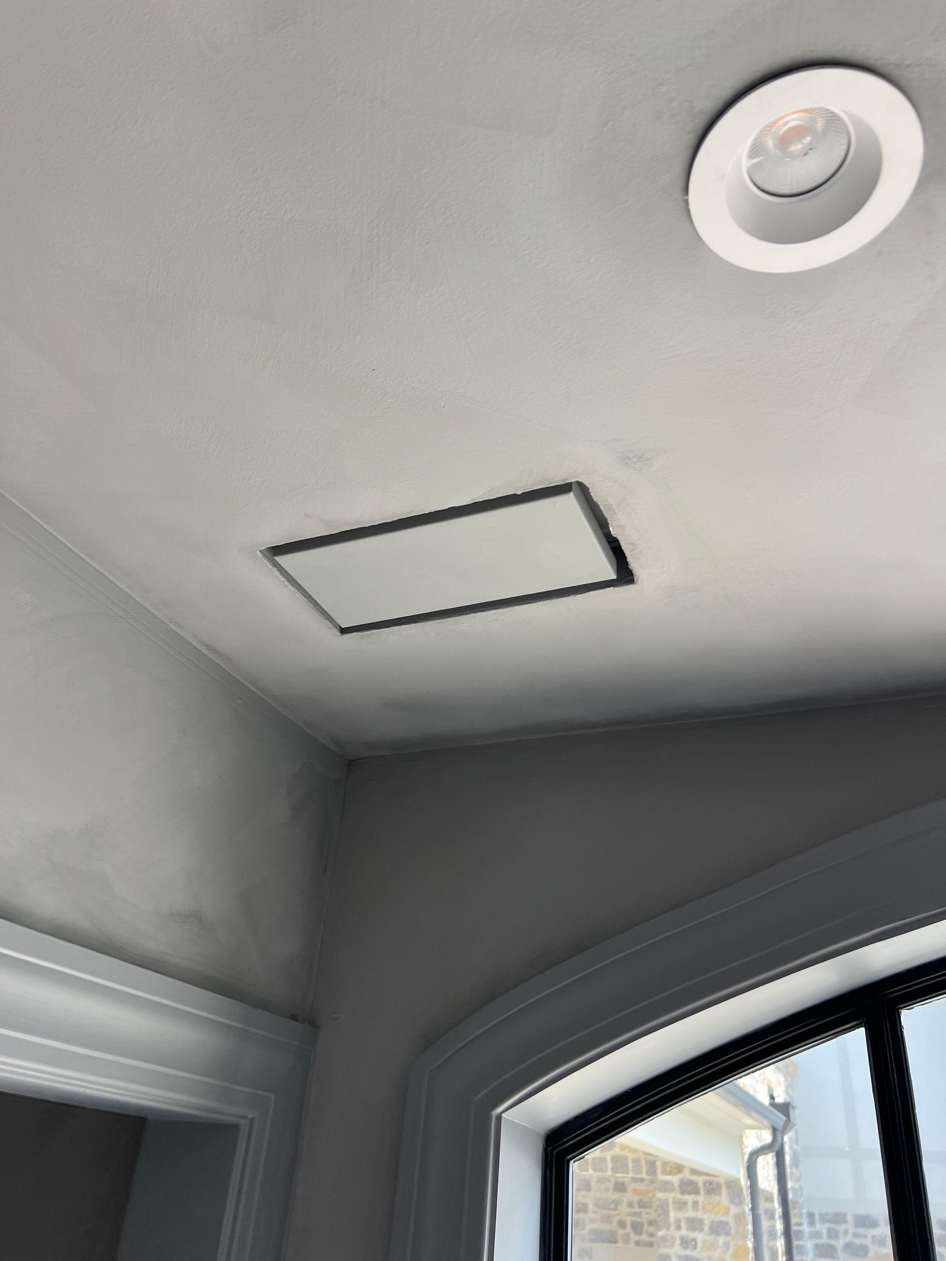 A ceiling with a square light on it and a window.
