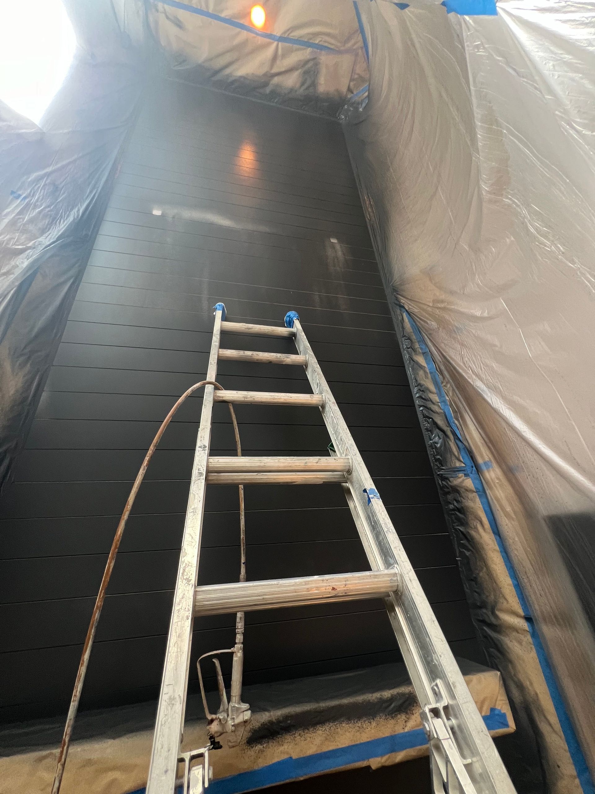 A ladder is being used to spray paint a wall.