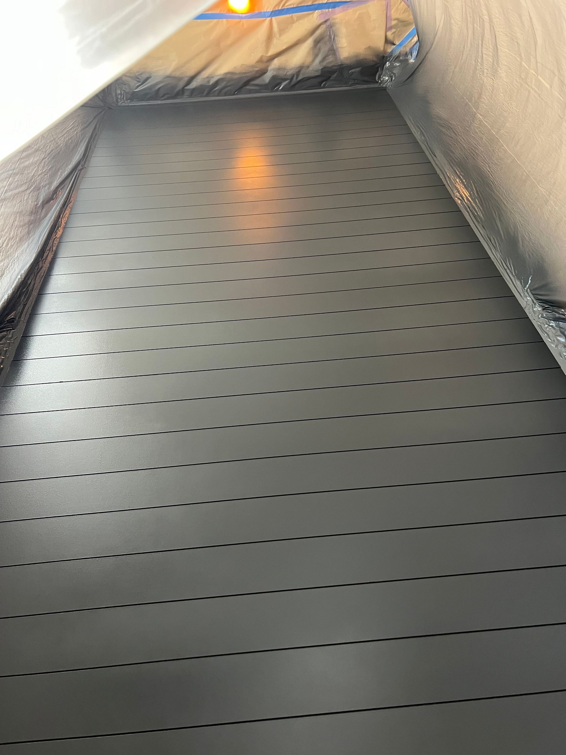 A black conveyor belt with holes in it is going down a staircase.