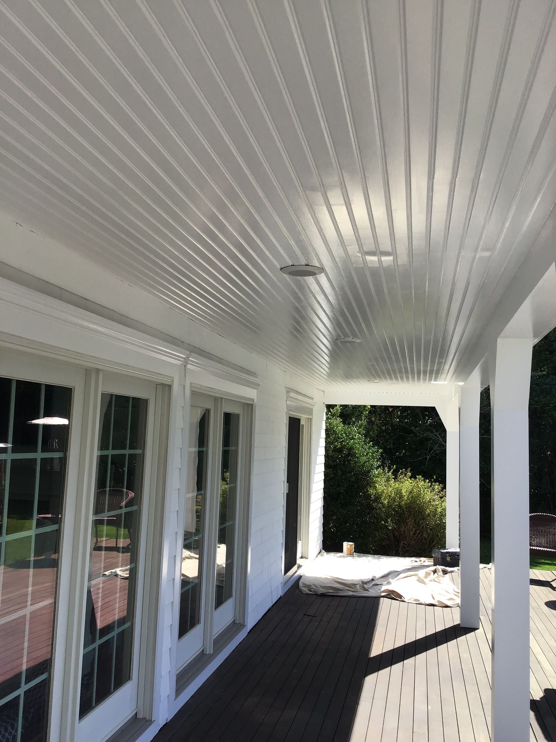 A white porch with a ceiling and a lot of windows