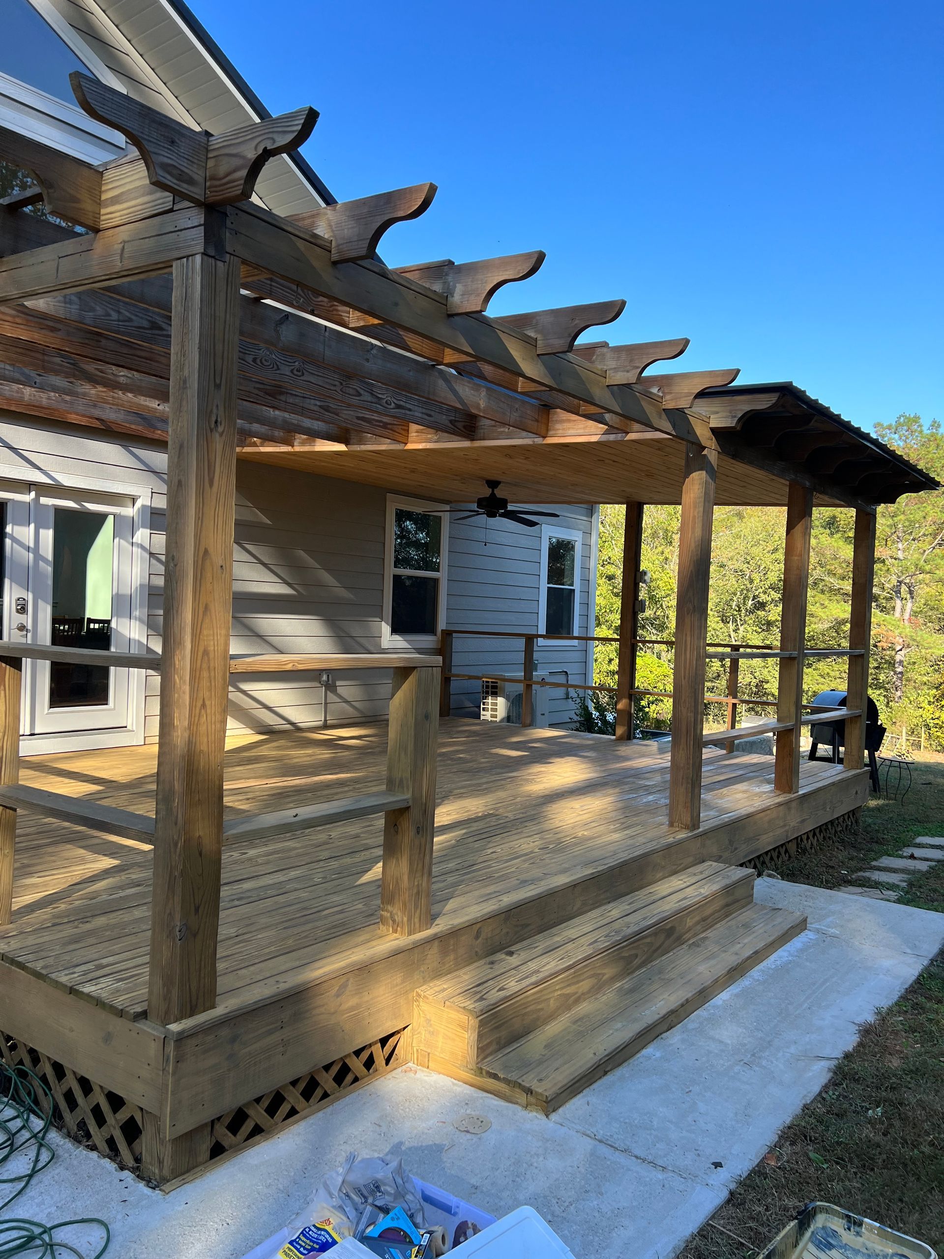 A wooden pergola is being built on the side of a house.