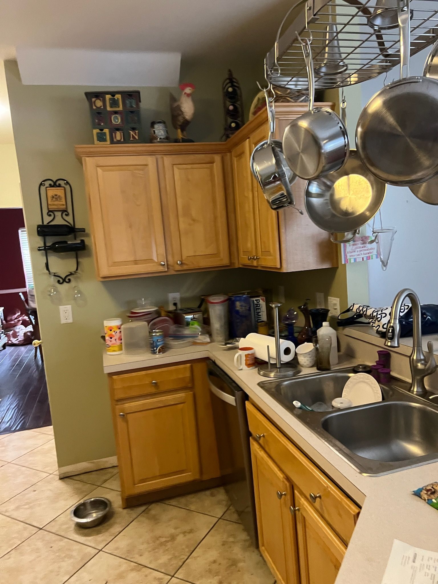 A kitchen with wooden cabinets , a sink , and pots and pans hanging from the ceiling.
