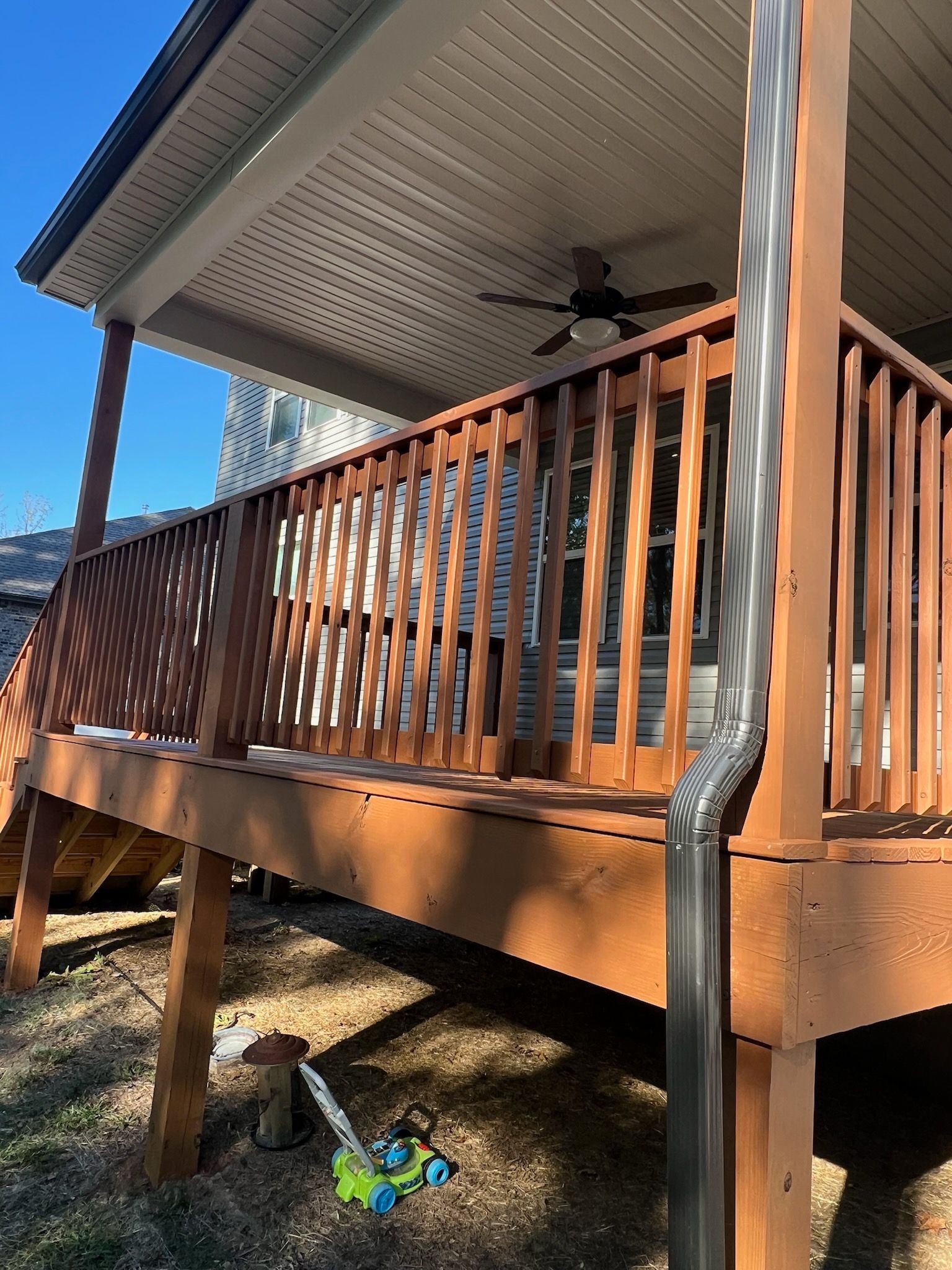 A wooden deck with a ceiling fan on top of it.