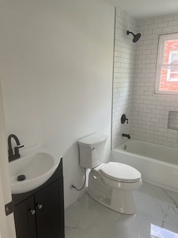 A bathroom with a toilet , sink and bathtub.