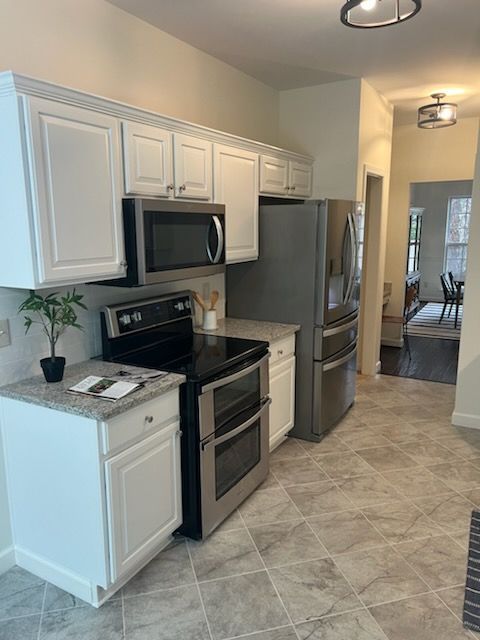 A kitchen with stainless steel appliances and white cabinets