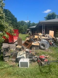A pile of junk is sitting in the grass in front of a house.