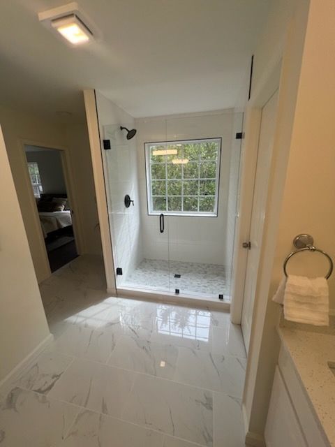 A bathroom with a walk in shower and a window.
