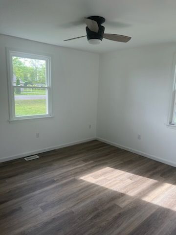 An empty room with a ceiling fan and a window.