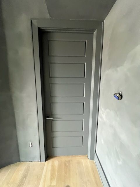 A gray door is in a room with a wooden floor.