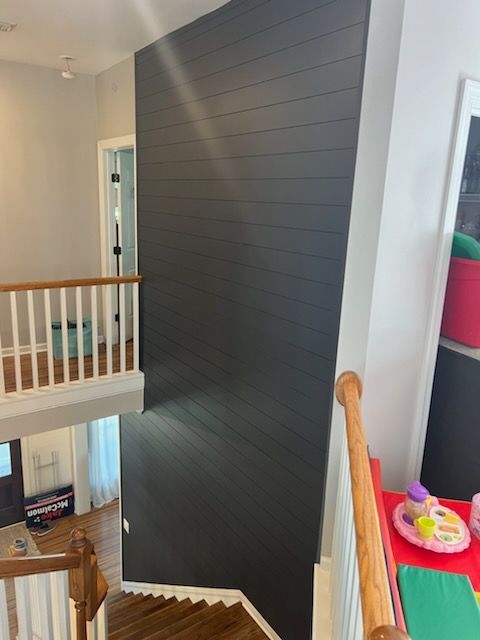 A staircase with a black wall and a white railing