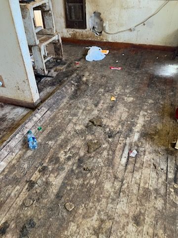 A dirty wooden floor in a room with a bottle of water on it.