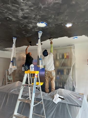 Two men are painting the ceiling of a room.