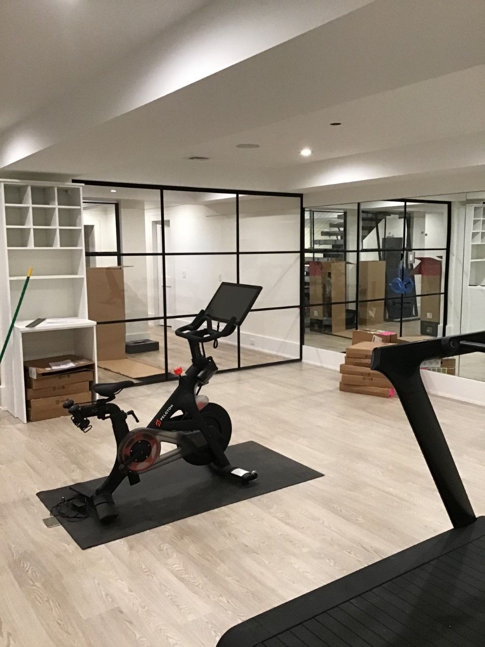 A bicycle is sitting on a mat in a gym next to a treadmill.