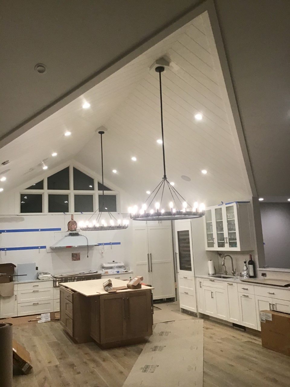 A kitchen under construction with a chandelier hanging from the ceiling