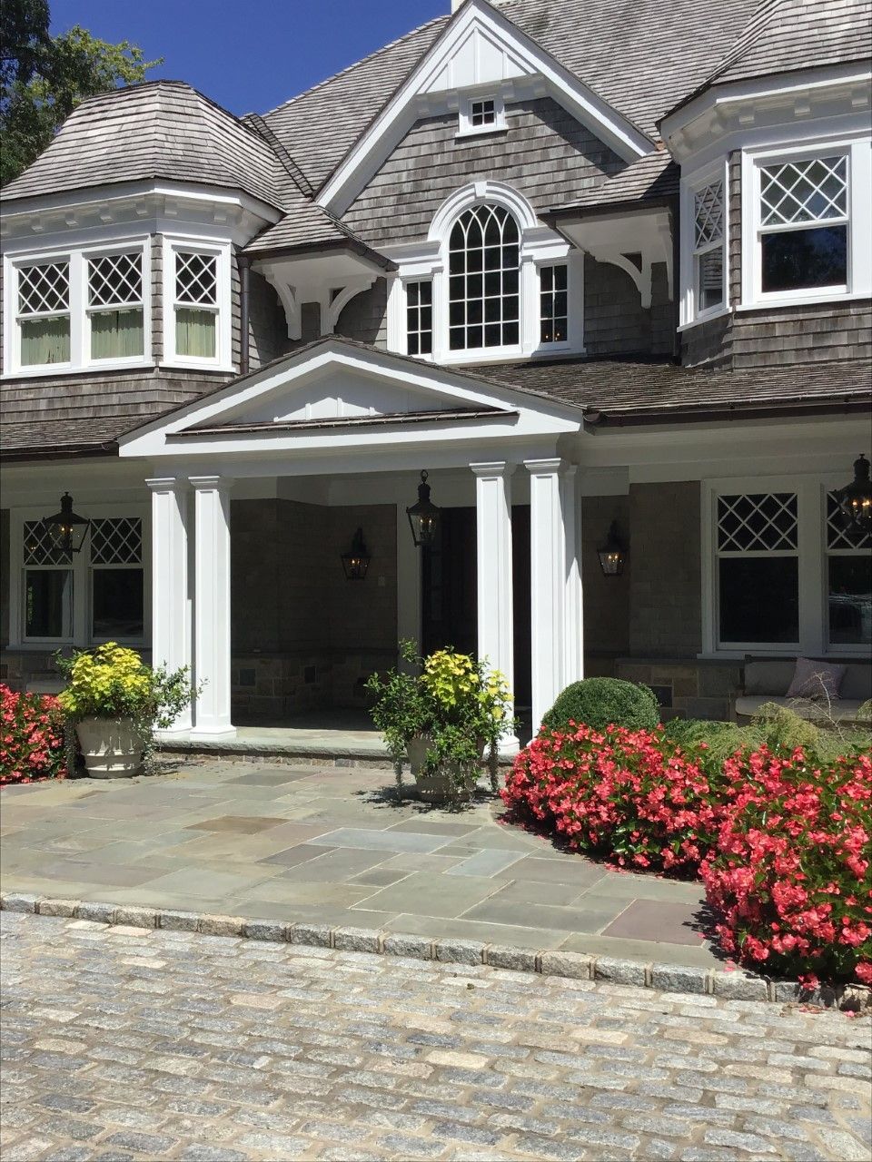 A large house with a porch and flowers in front of it
