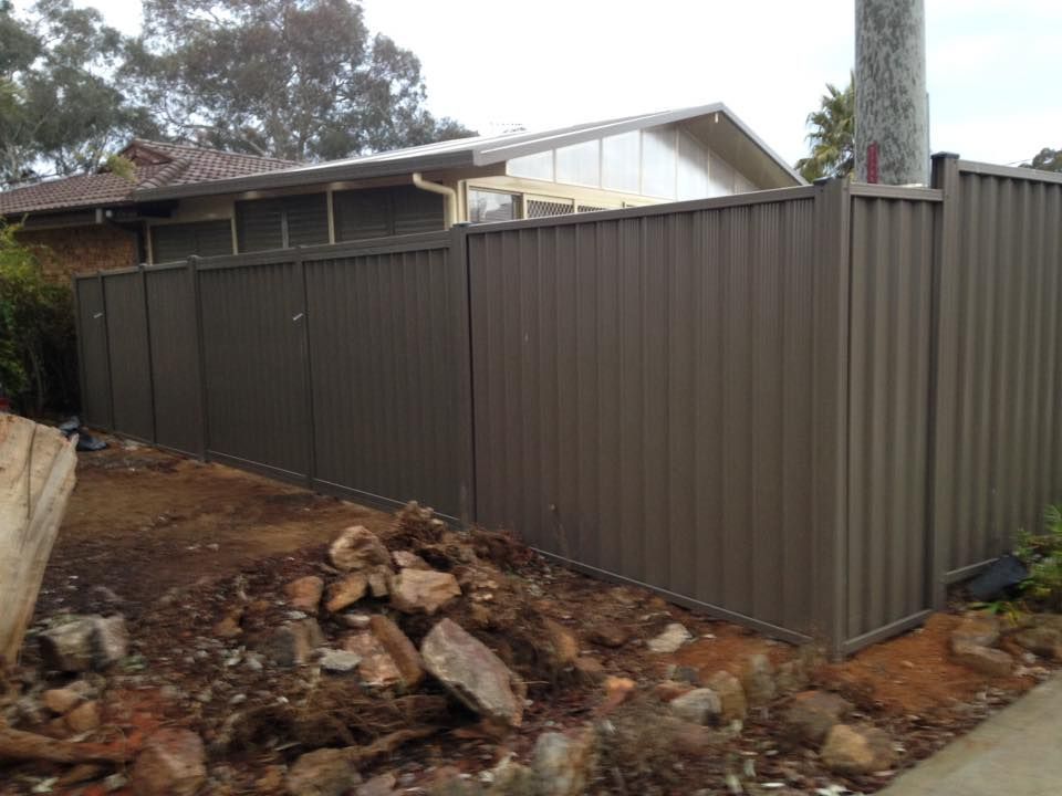 A fence is surrounding a pile of rocks in front of a house.